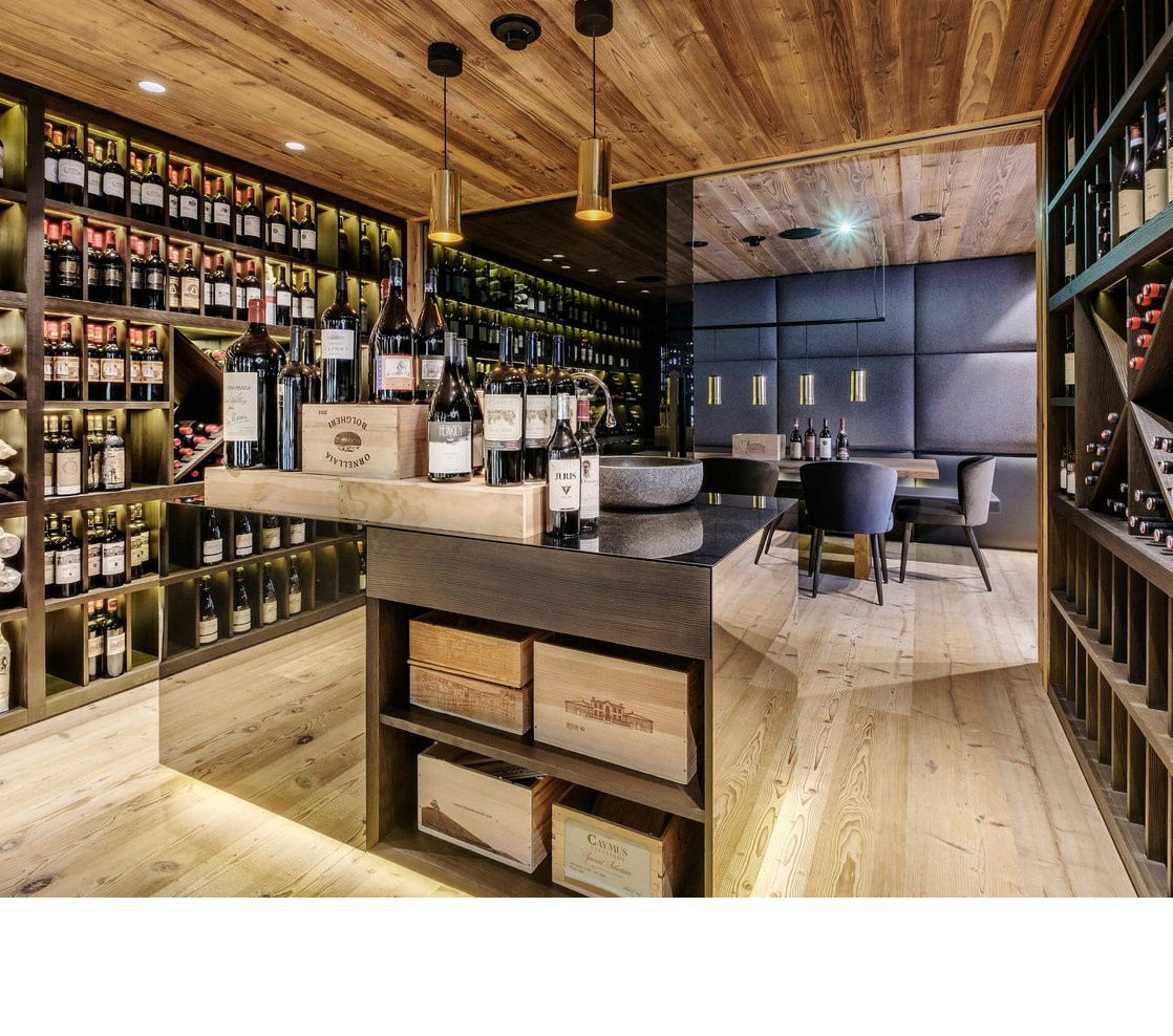 Weinkeller im Hotel Severin*s – The Alpine Retreat in Lech Moderner Weinkeller im Hotel Severin*s, gefüllt mit Weinflaschen, Holzregalen und einem Tisch mit Stühlen.